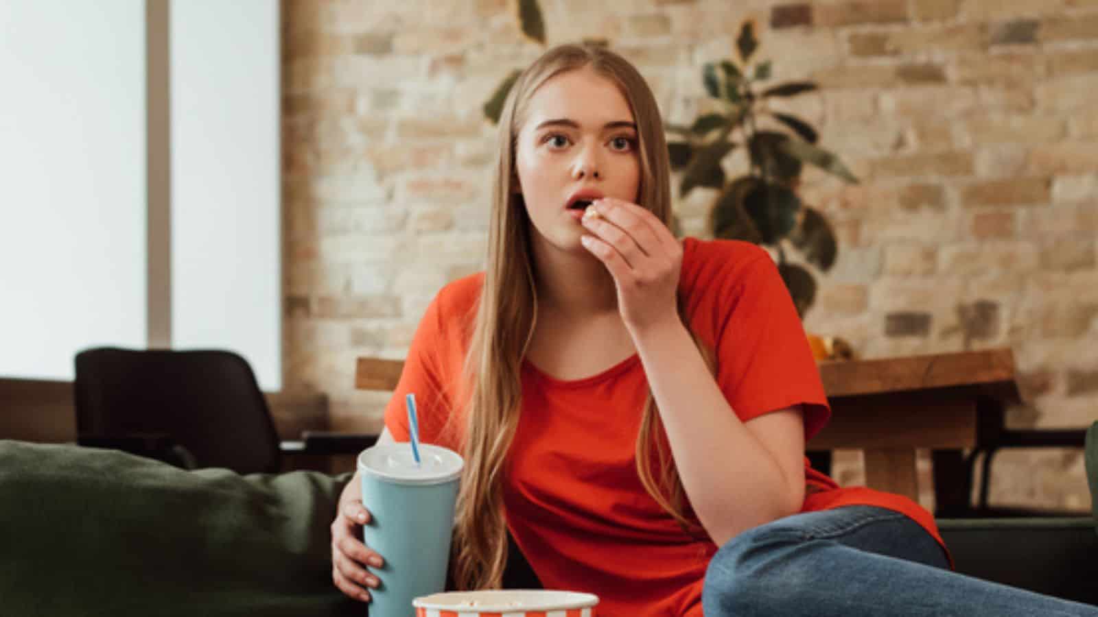Panoramic shot of attractive girl eating popcorn