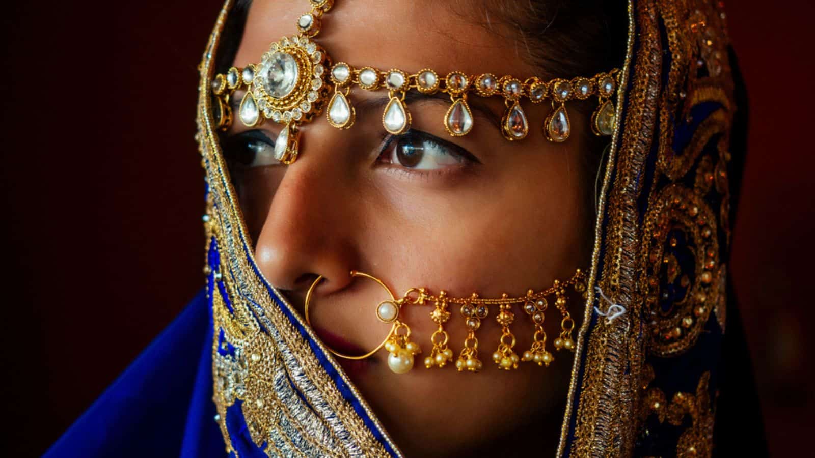 Portrait indian beautiful female in golden rich jewelery and tradition saree face closeup professional make-up wearing bindi on head
