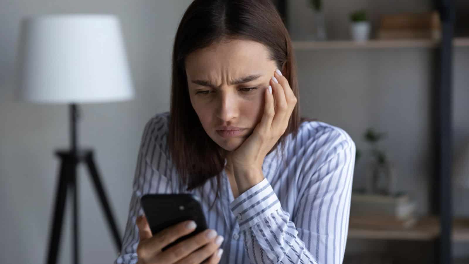 Portrait of beautiful angry woman using mobile phone at home