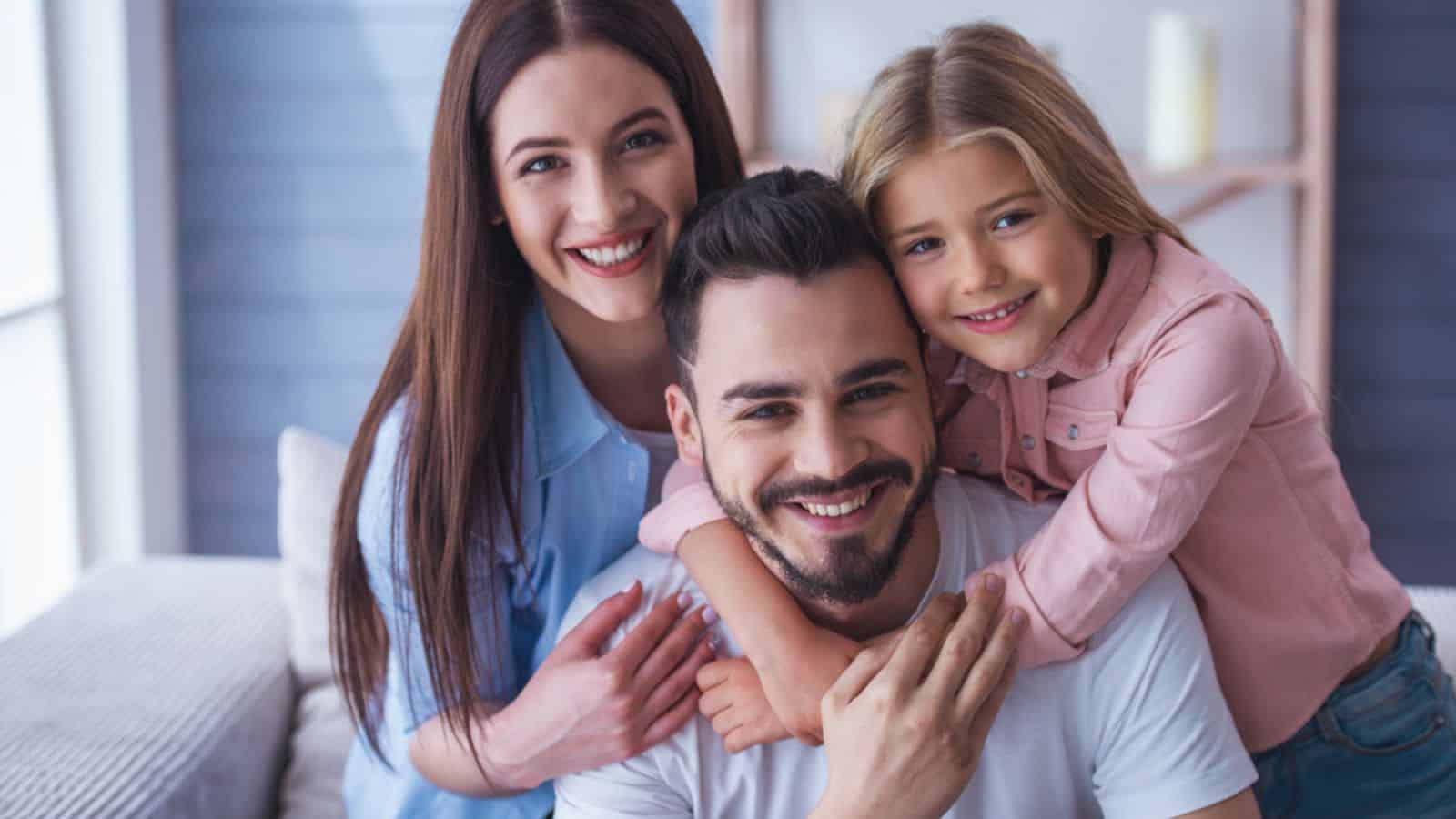 Portrait of beautiful young mother, father and their daughter hugging
