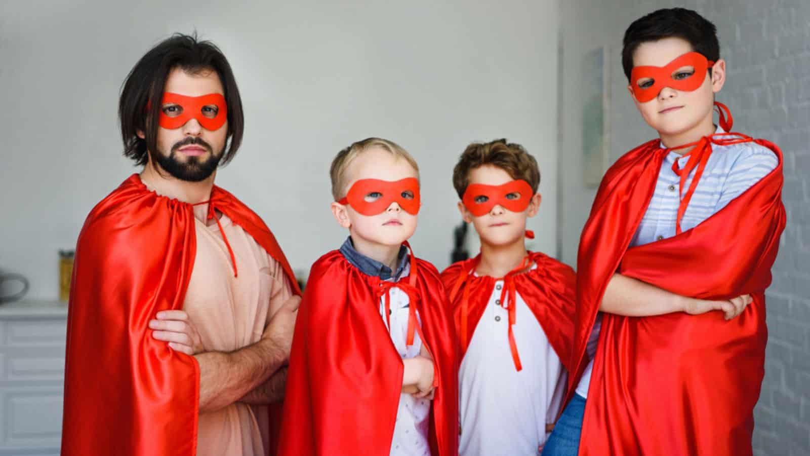 Portrait of father and little sons in red superhero costumes