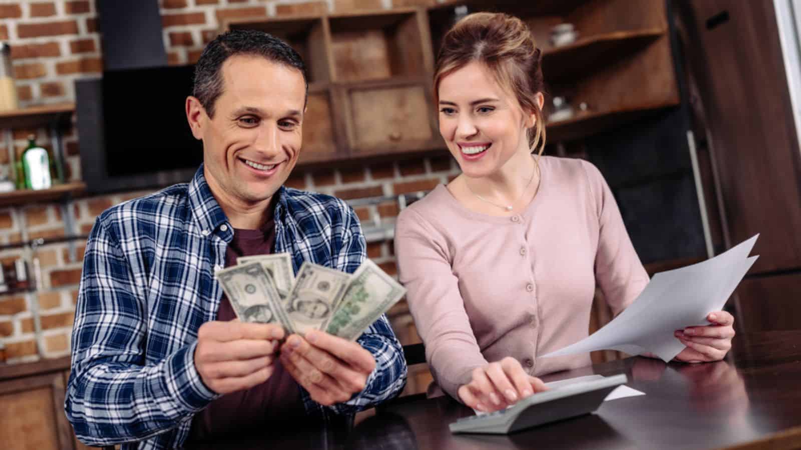 Portrait of happy couple counting money together at home