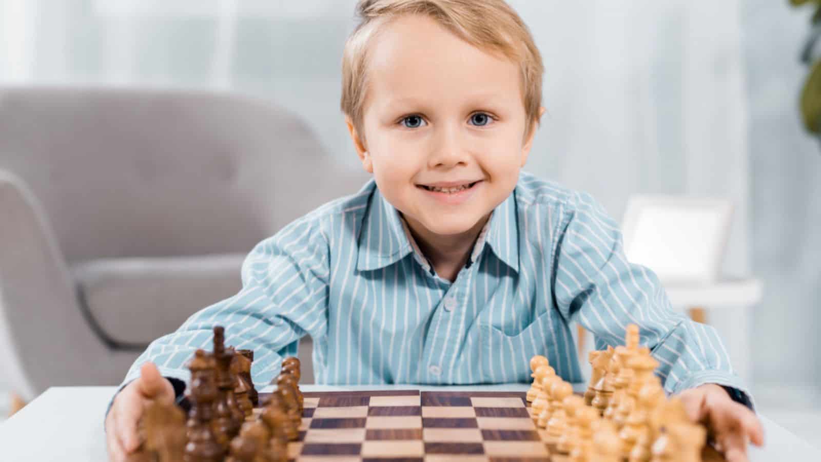 Portrait of happy little boy looking at camera near chessboard