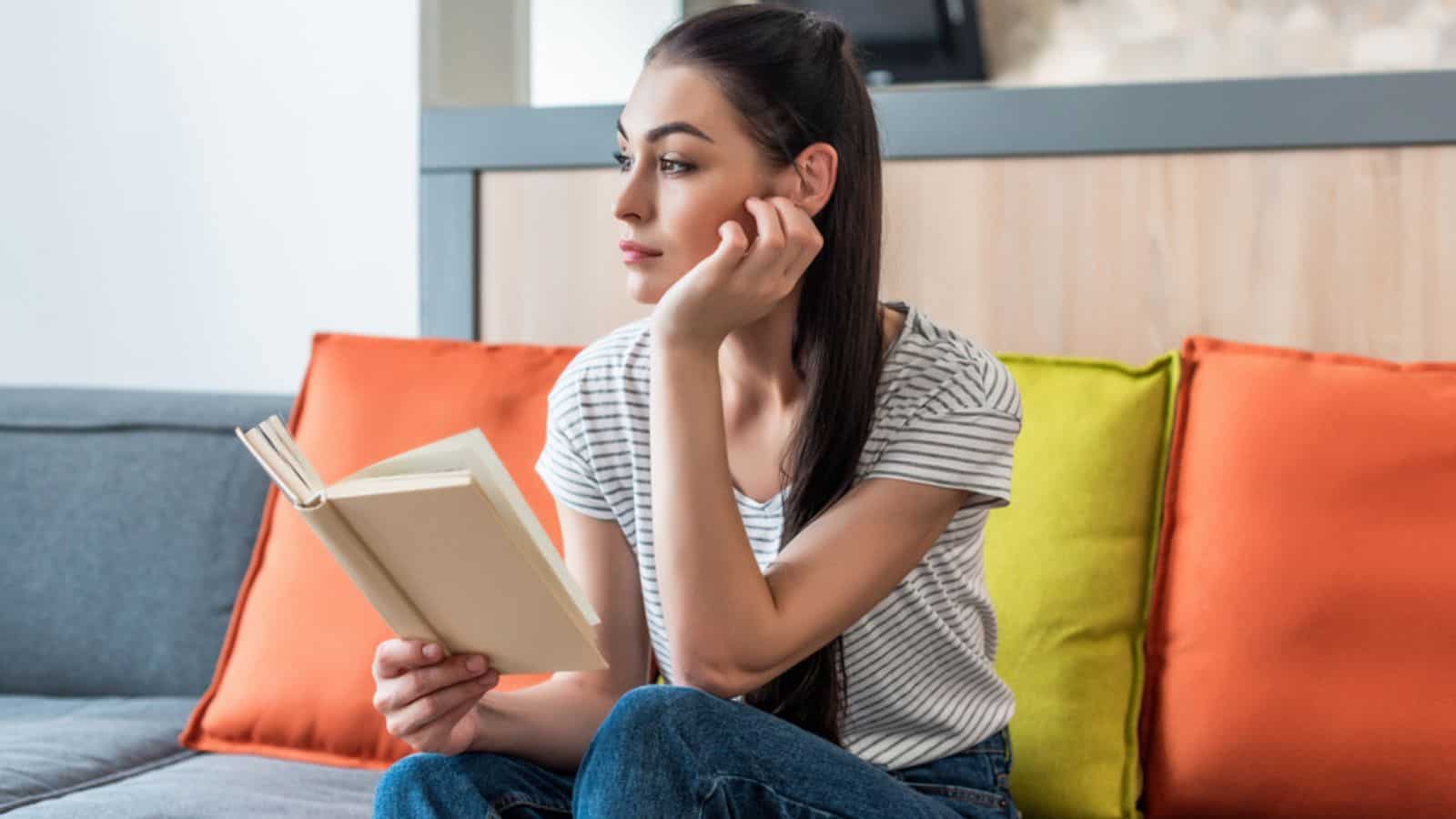 Portrait of pensive woman looking away while reading book