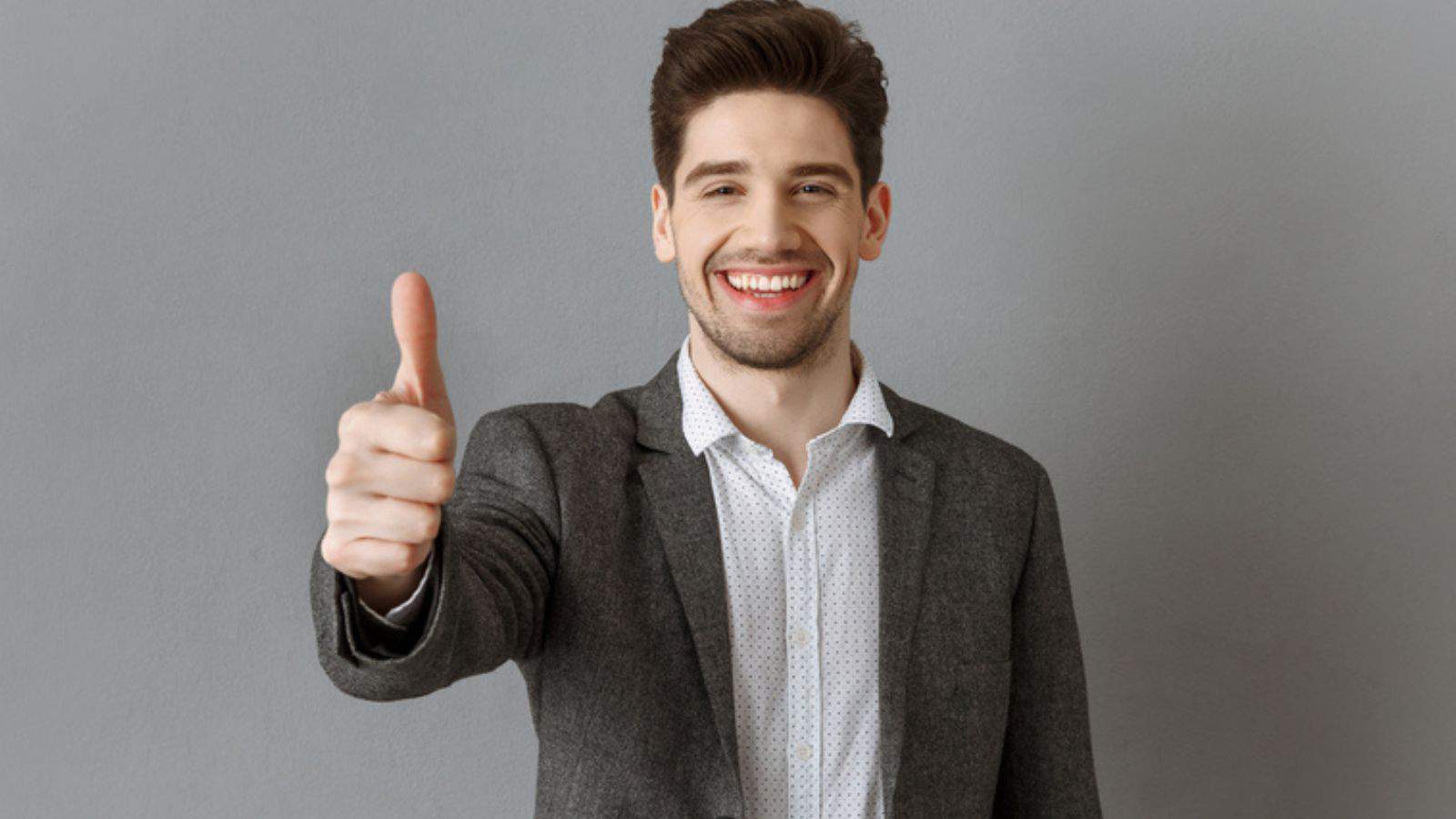 Portrait of smiling businessman in suit showing thumb up