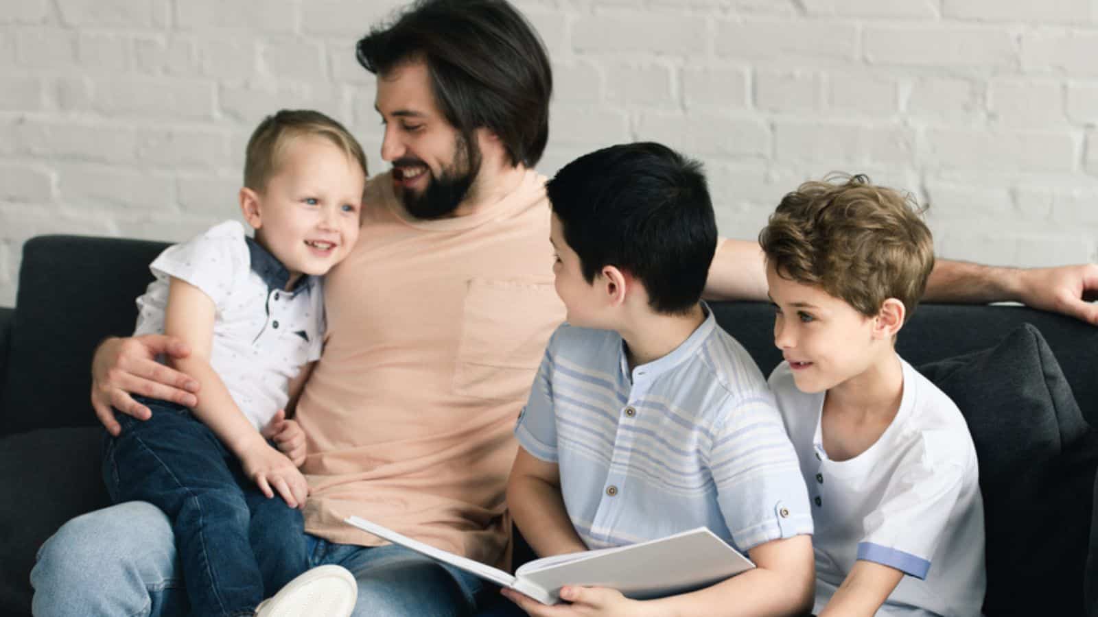 Portrait of smiling father and sons reading book together