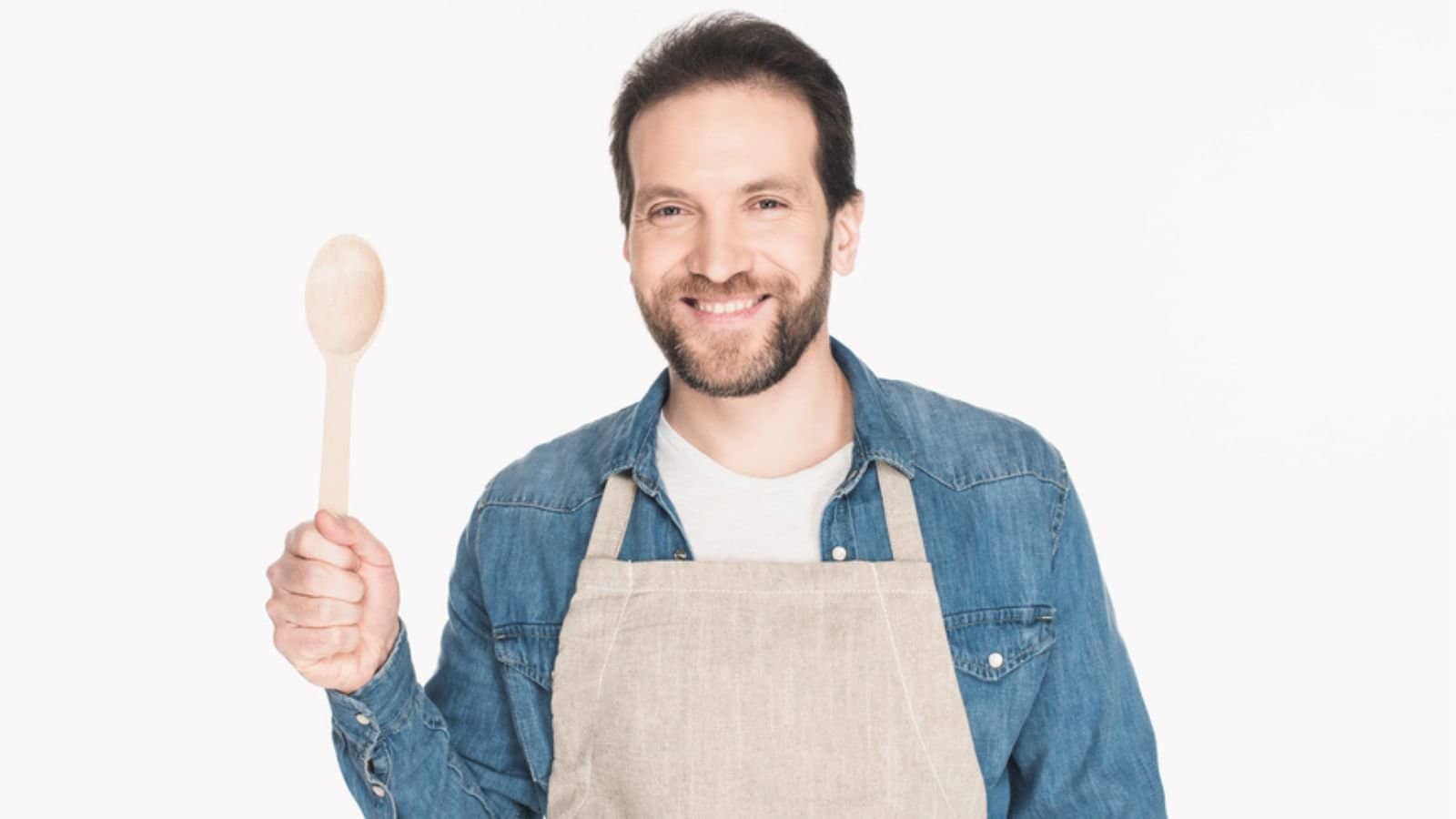 Portrait of smiling man in apron with wooden spoon