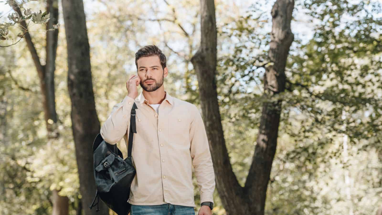 Portrait of young man with backpack talking on smartphone