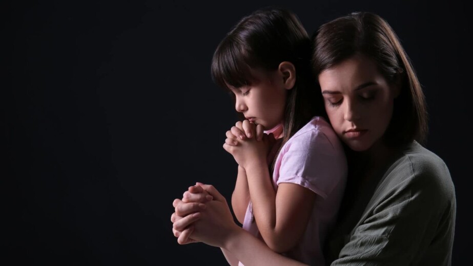 Praying Mother and Daughter on Dark Background