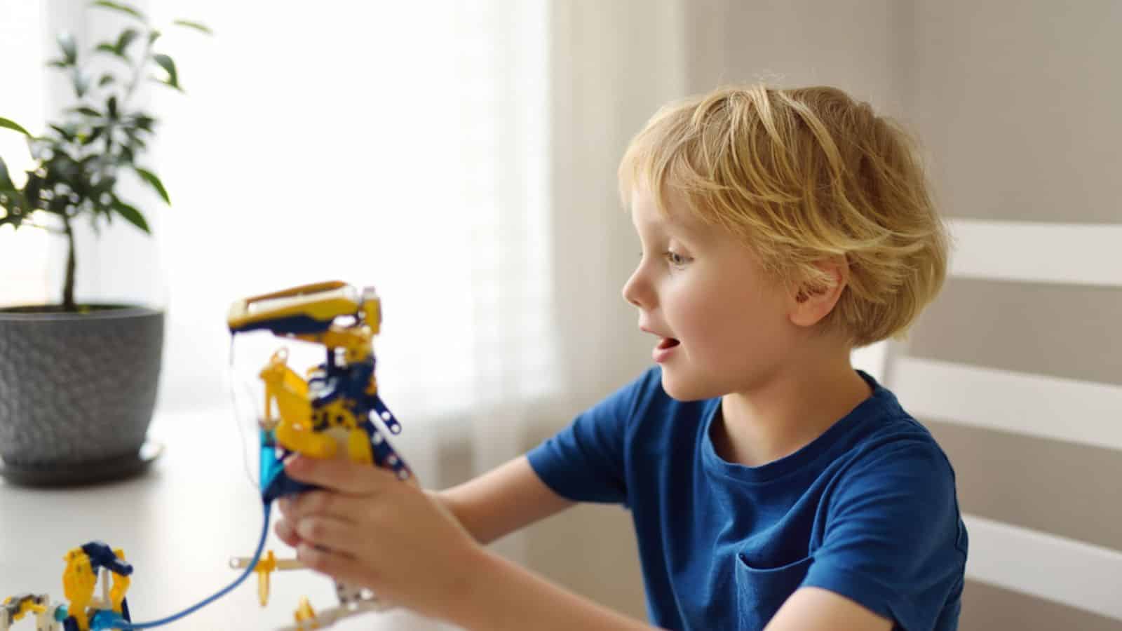 Preschooler boy playing with robot toy at home