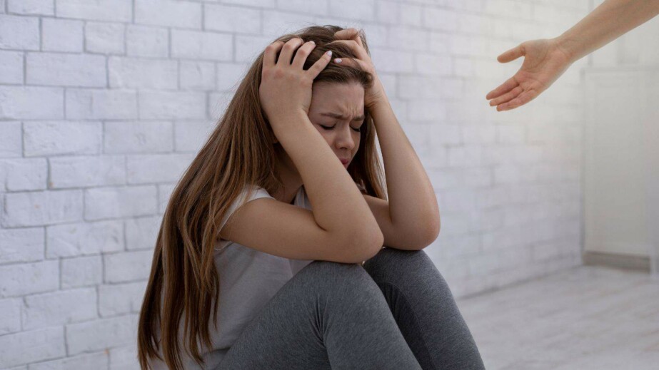 Psychologist hand helping sad young woman to get rid of depression