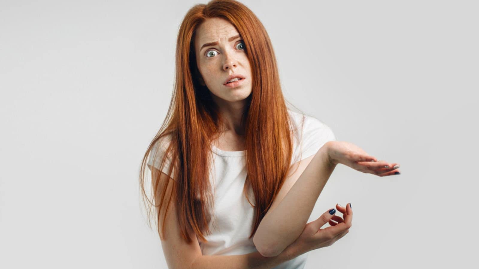 Puzzled and clueless young redhead woman with arms