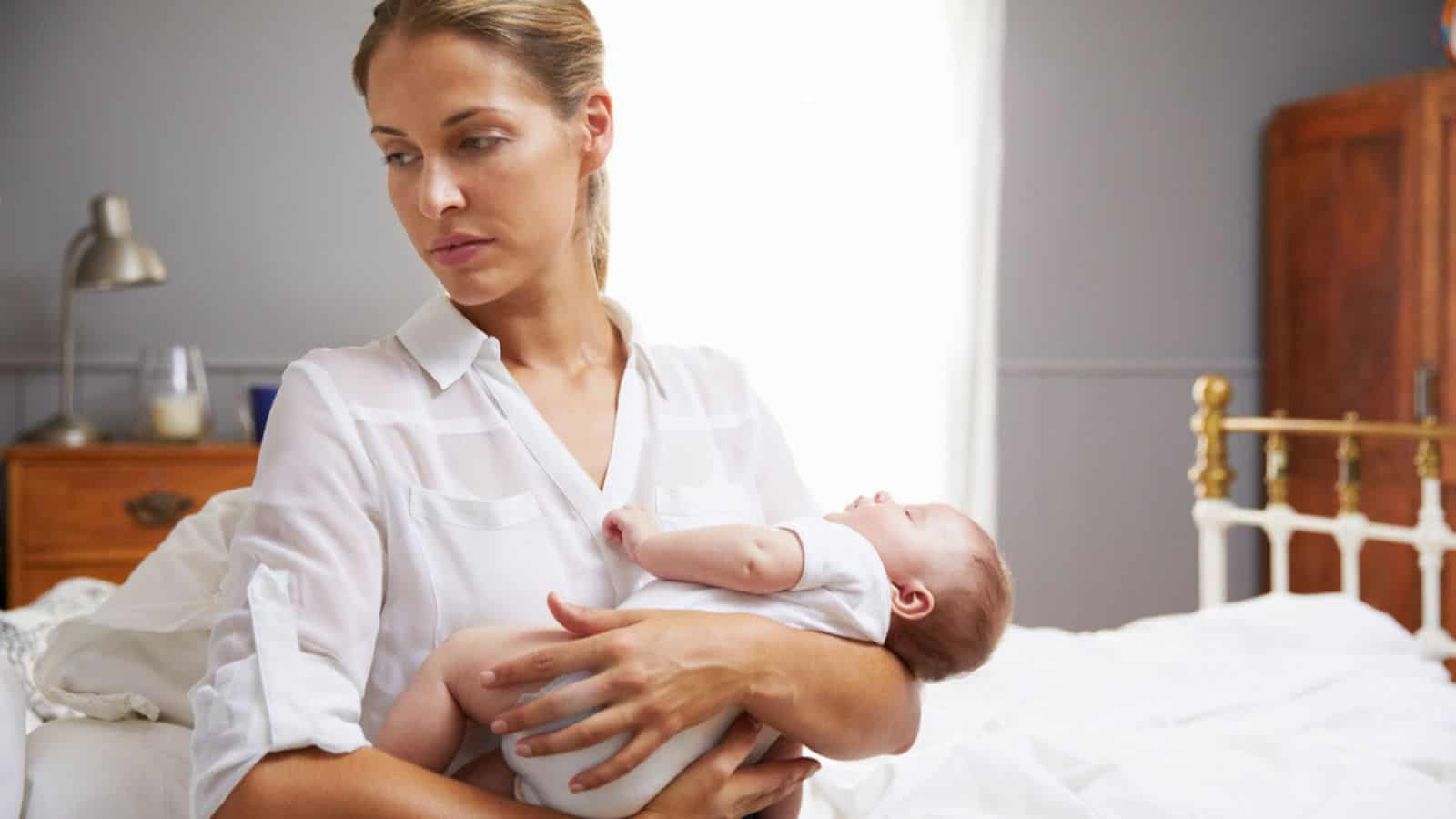 Sad Mother Holding Baby In Bedroom