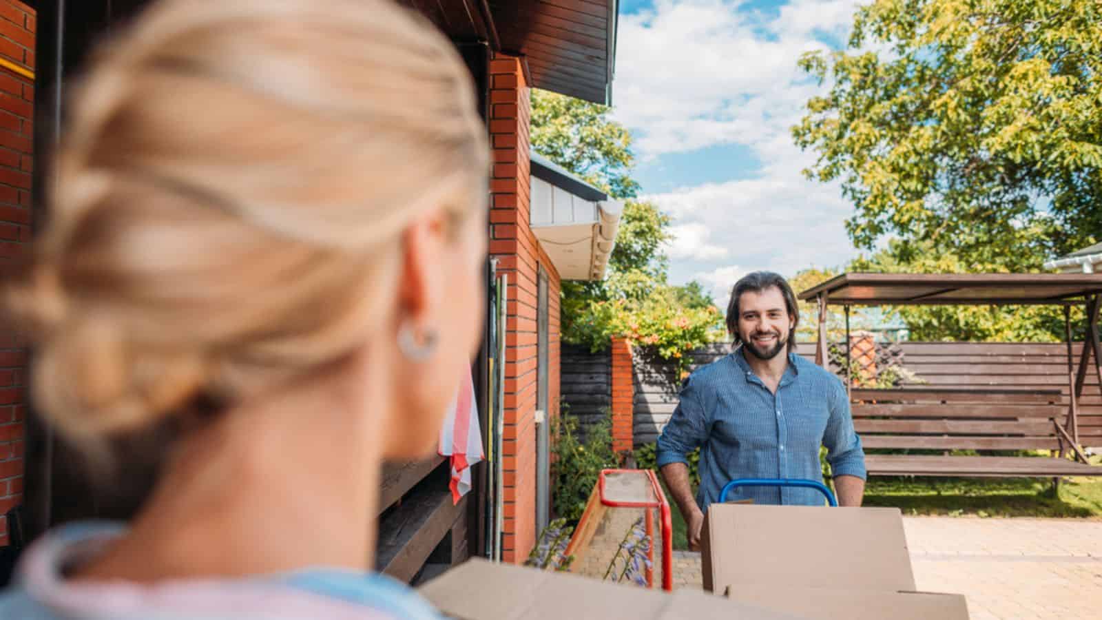 Selective focus of man with handle tray with cardboard boxes looking at new house