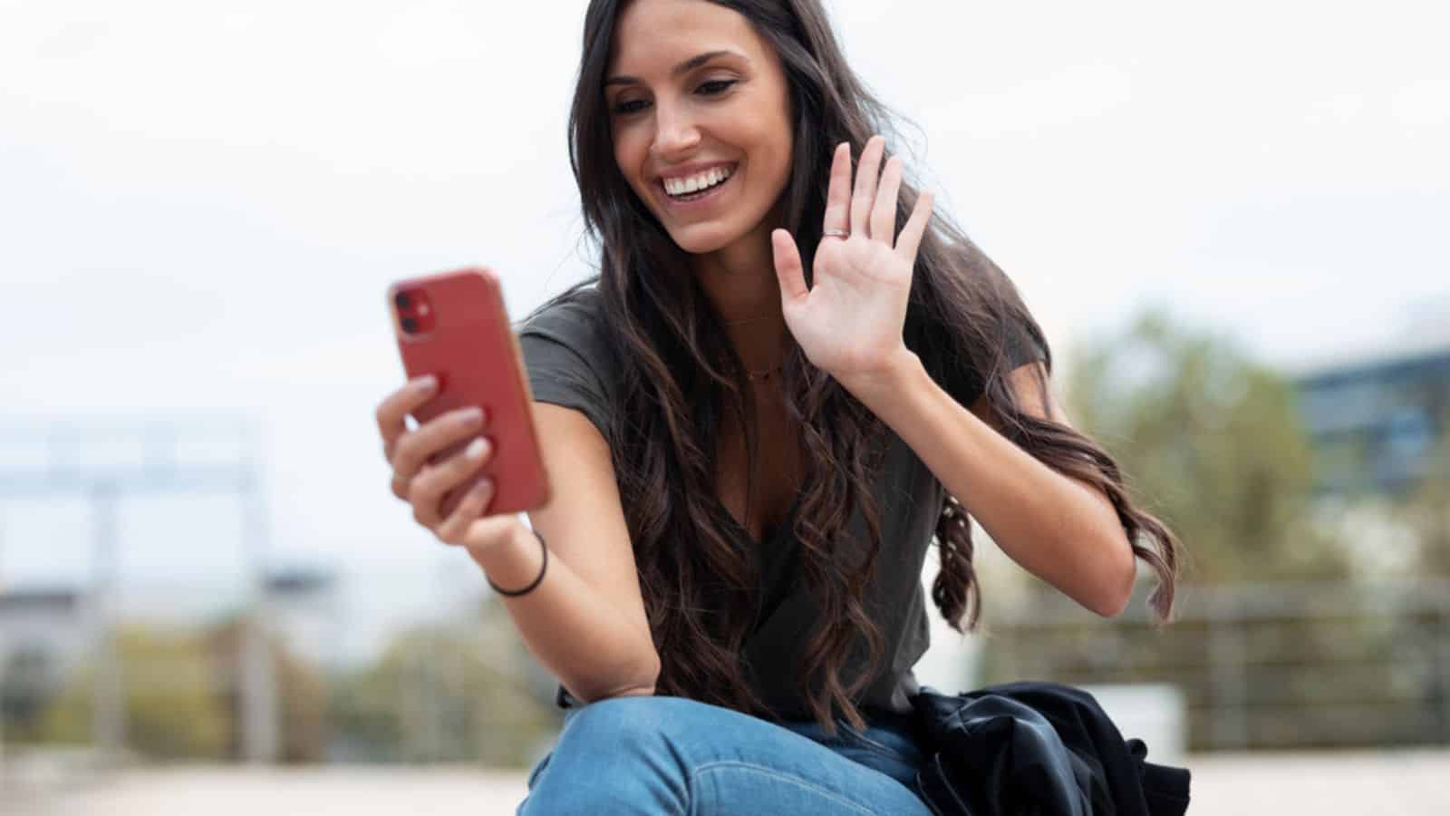 Shot of pretty young woman waving hand while making video call with smartphone
