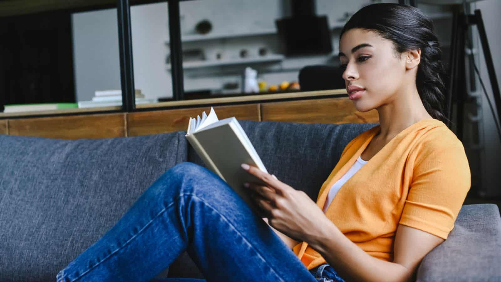 Side view of beautiful mixed race girl in orange shirt reading