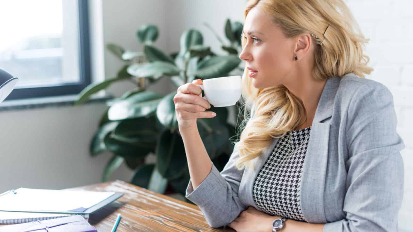 Side view of businesswoman drinking coffee at work