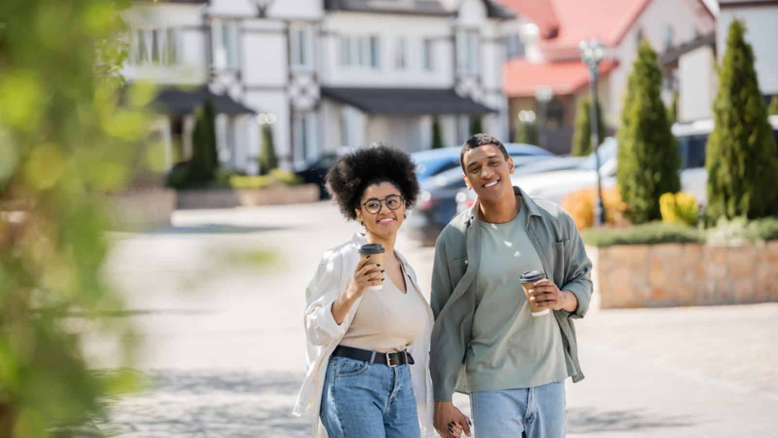 Smiling african american woman with coffee to go walking with boyfriend