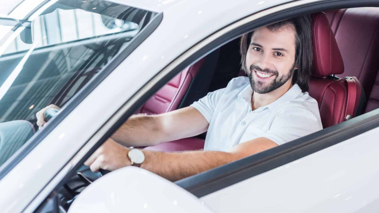 Smiling bearded man sitting in new car
