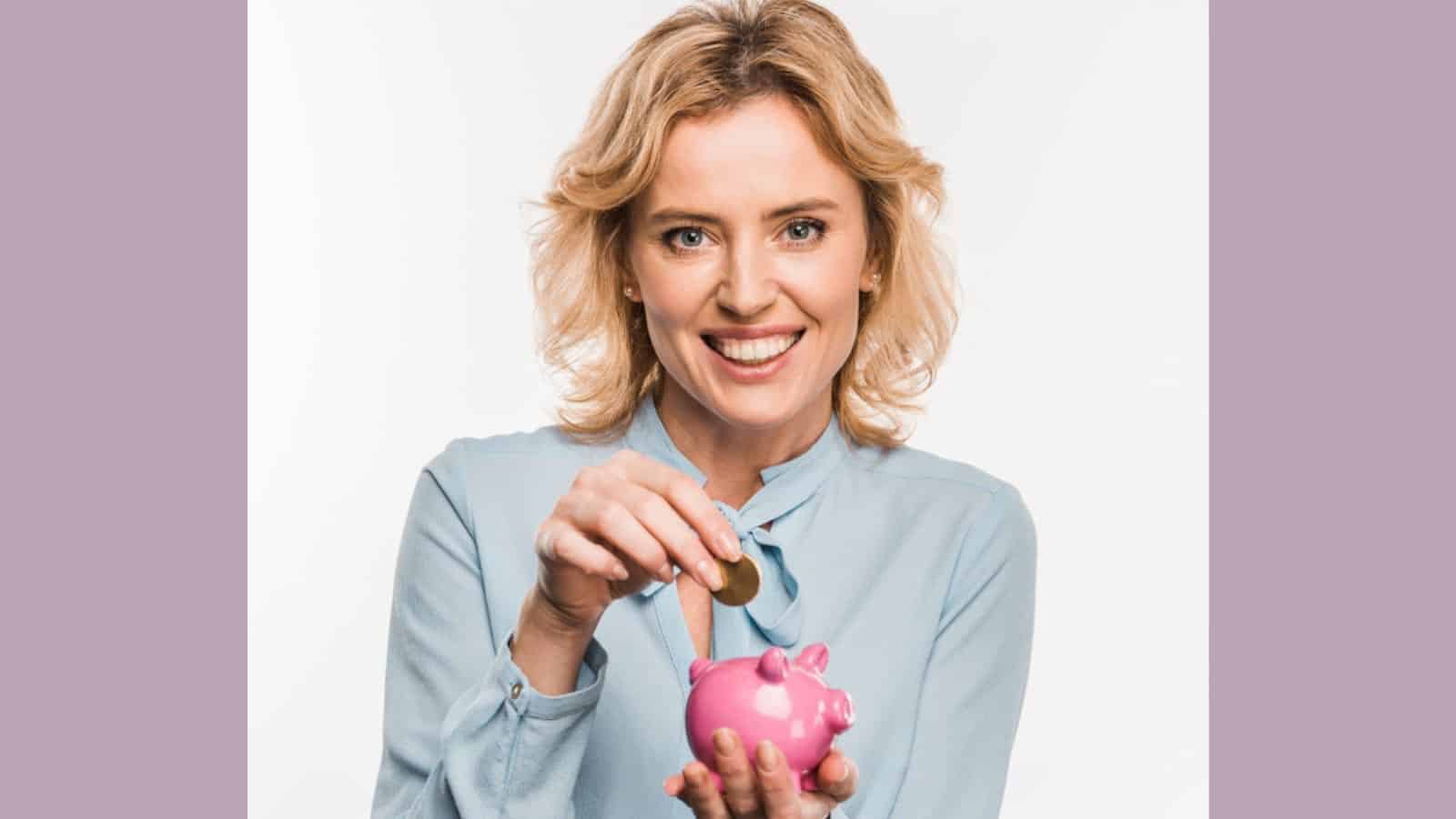 Smiling businesswoman holding piggy bank and coin