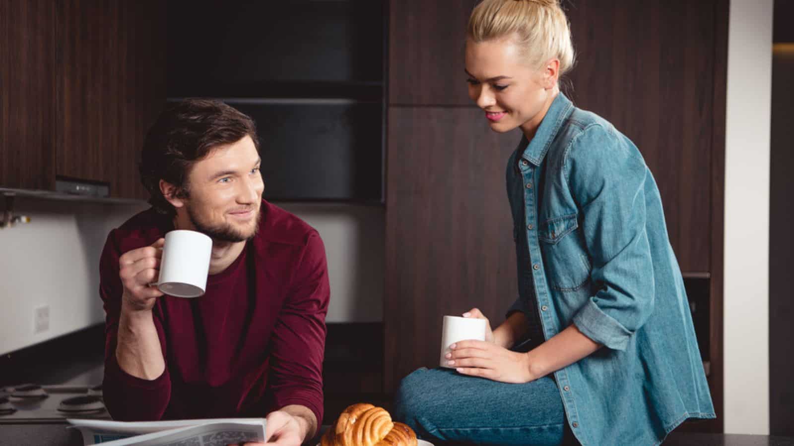 Smiling couple holding coffee cups and reading newspaper