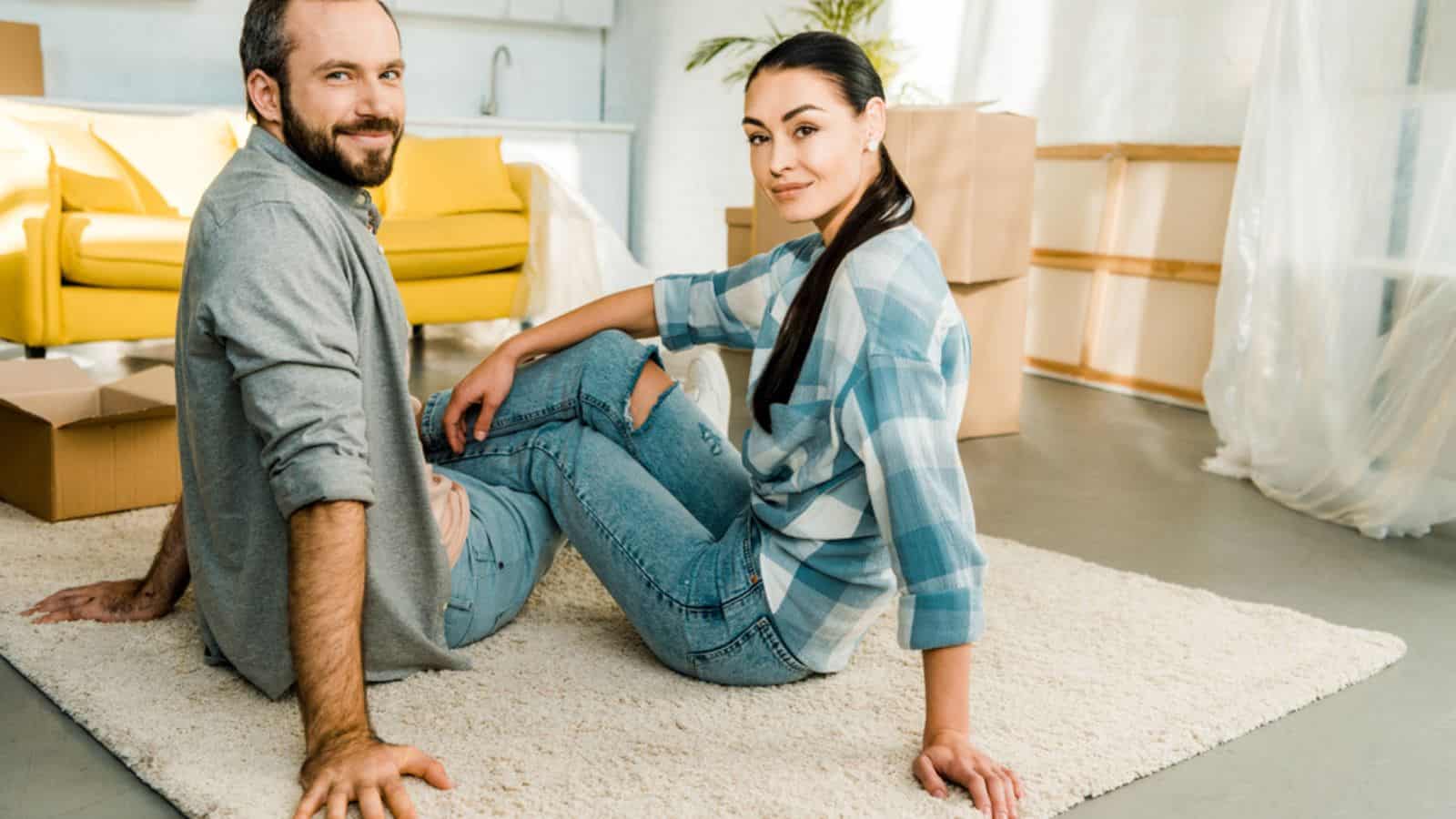 Smiling husband and wife sitting on floor