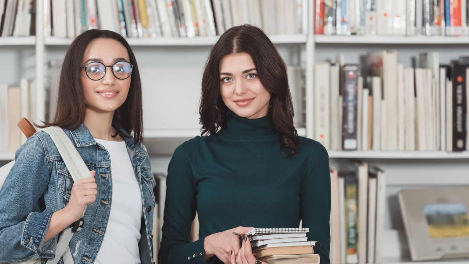 Smiling multicultural friends looking at camera in library