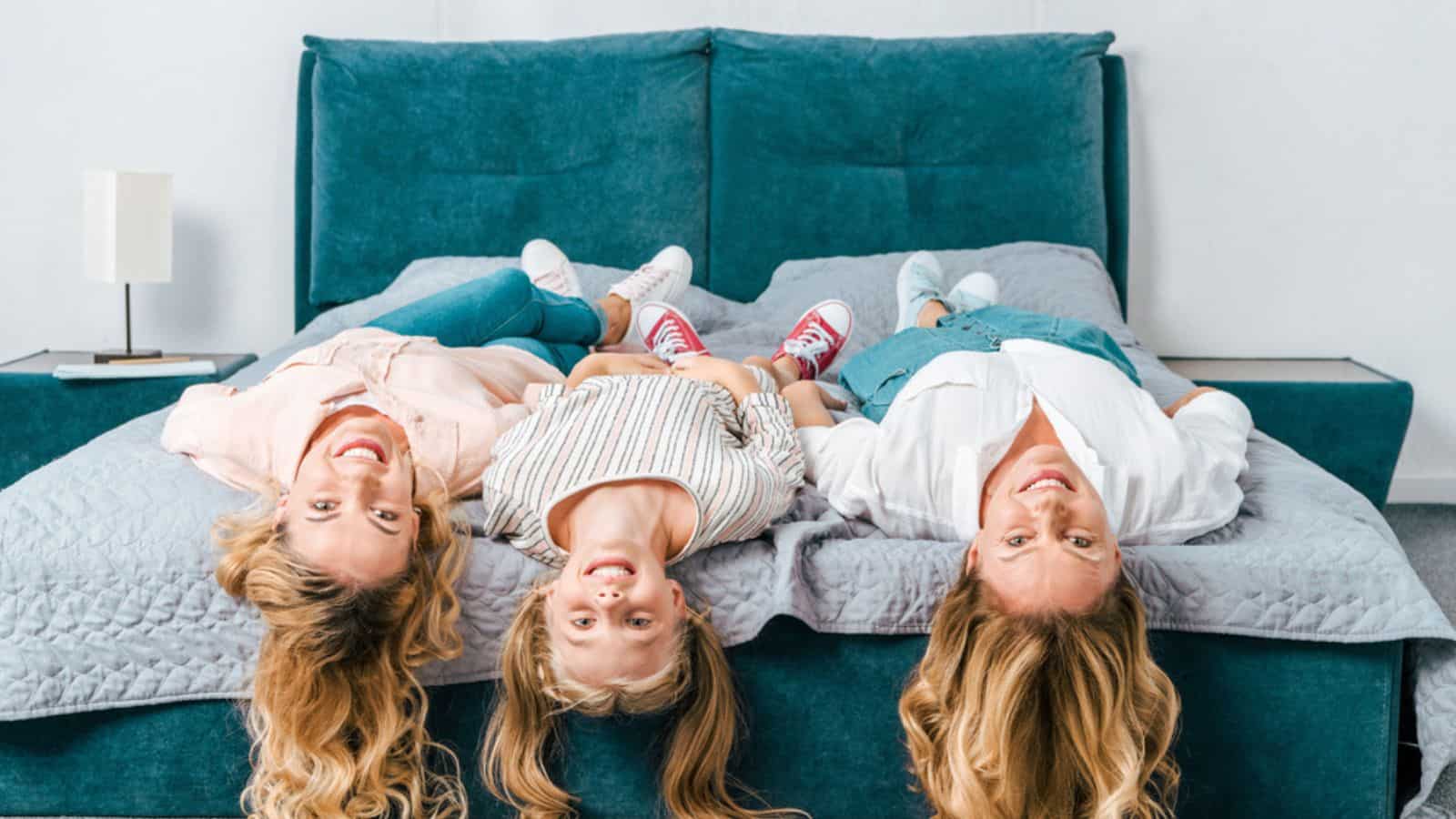 Smiling three generations of women lying on bed and looking at camera