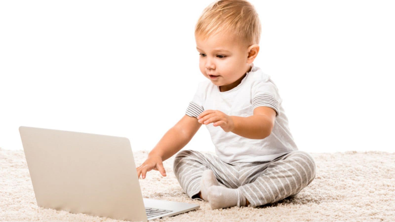 Smiling toddler boy sitting with laptop on carpet