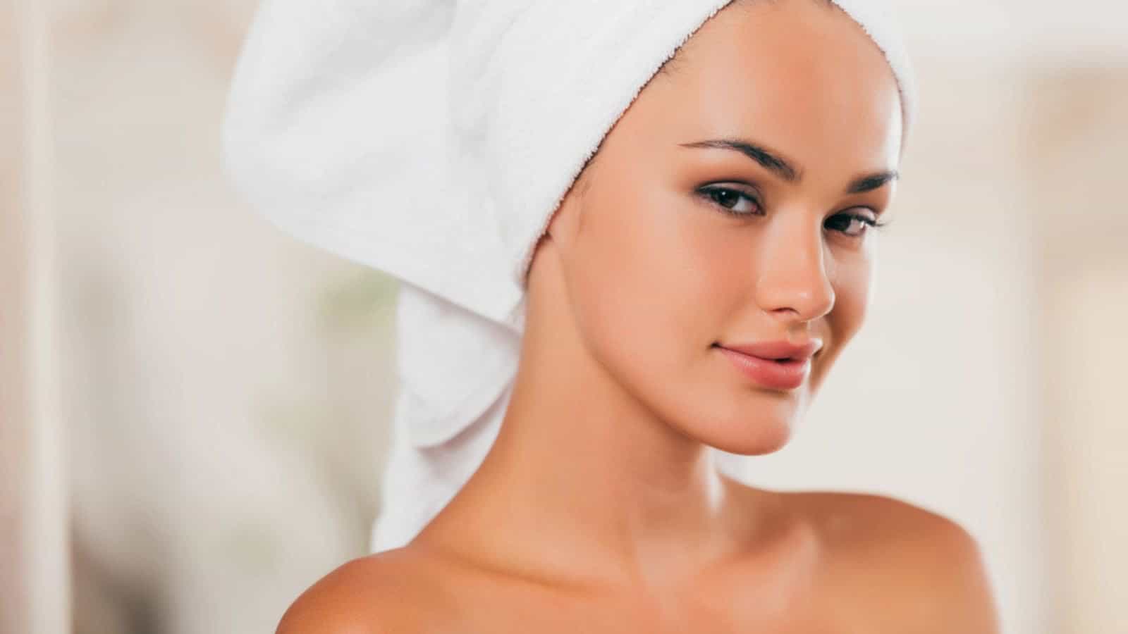 Smiling woman relaxing with towel on head at spa salon
