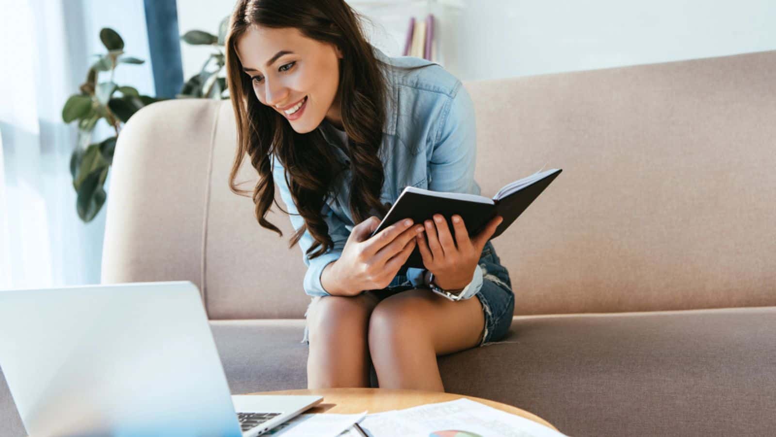 Smiling young businesswoman with notebook remote working at home