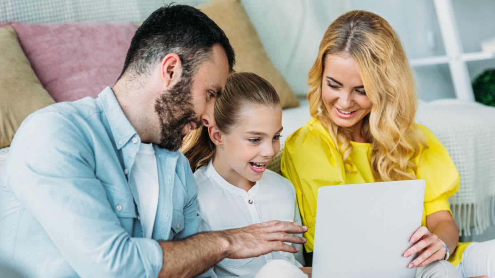 Smiling young family using laptop together