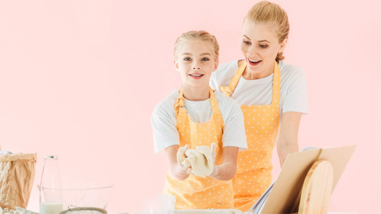 Surprised young mother looking at daughter kneading dough