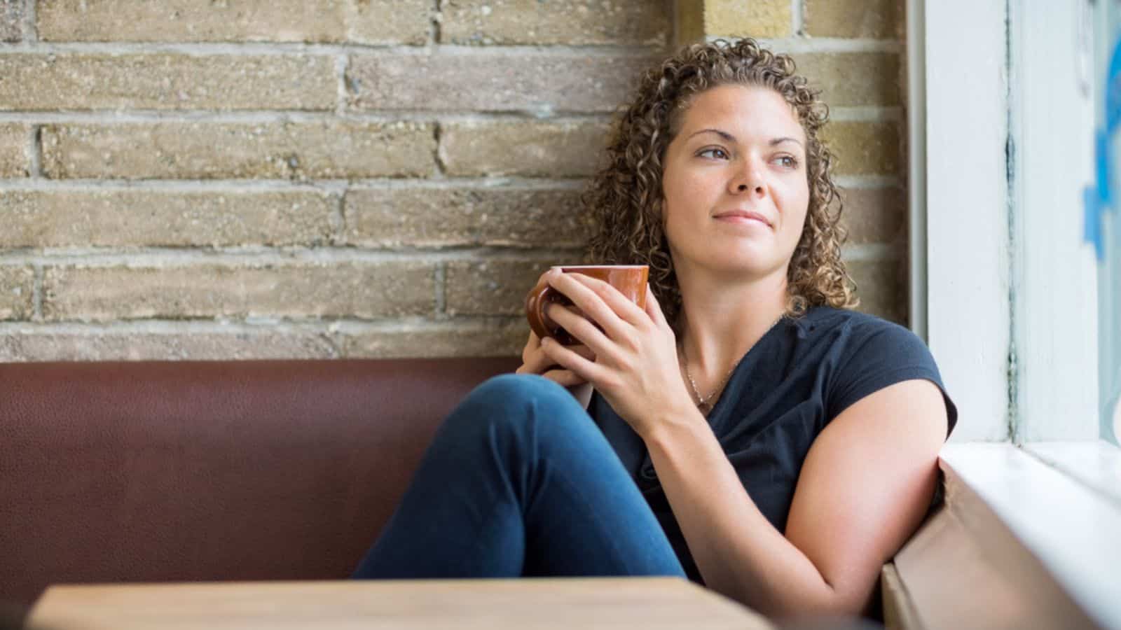Thinking Woman Holding Coffee Mug In Cafe
