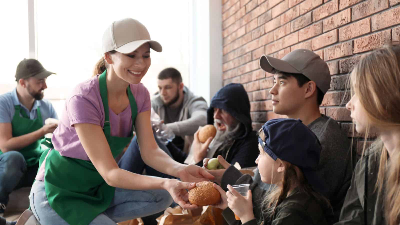 Volunteers Giving Food to Poor People Indoors 