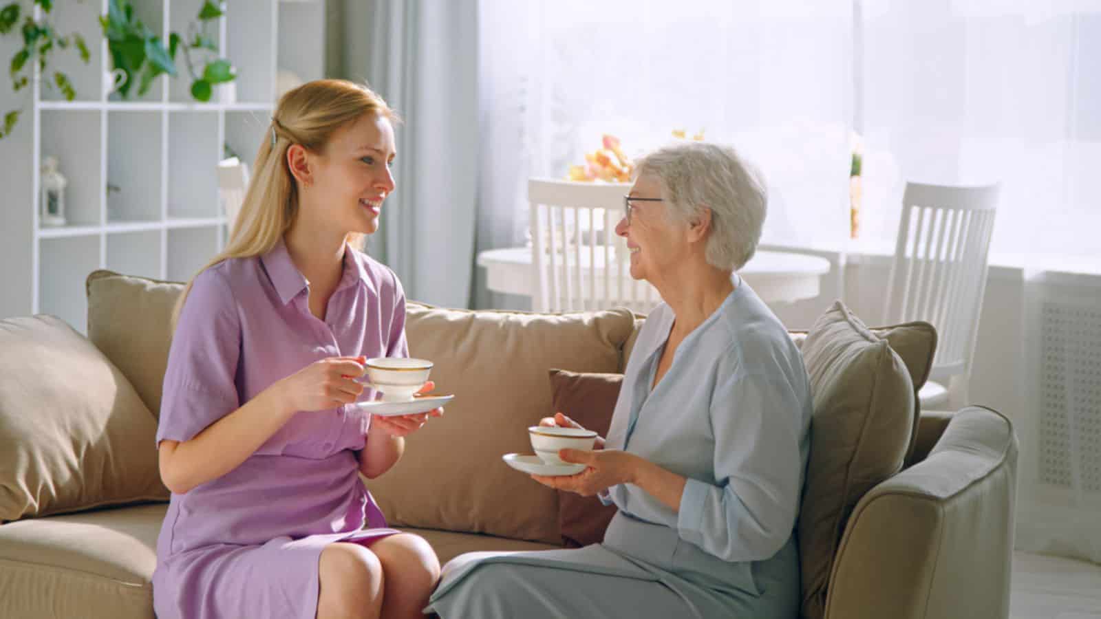 Woman and elderly mother drinking tea at home