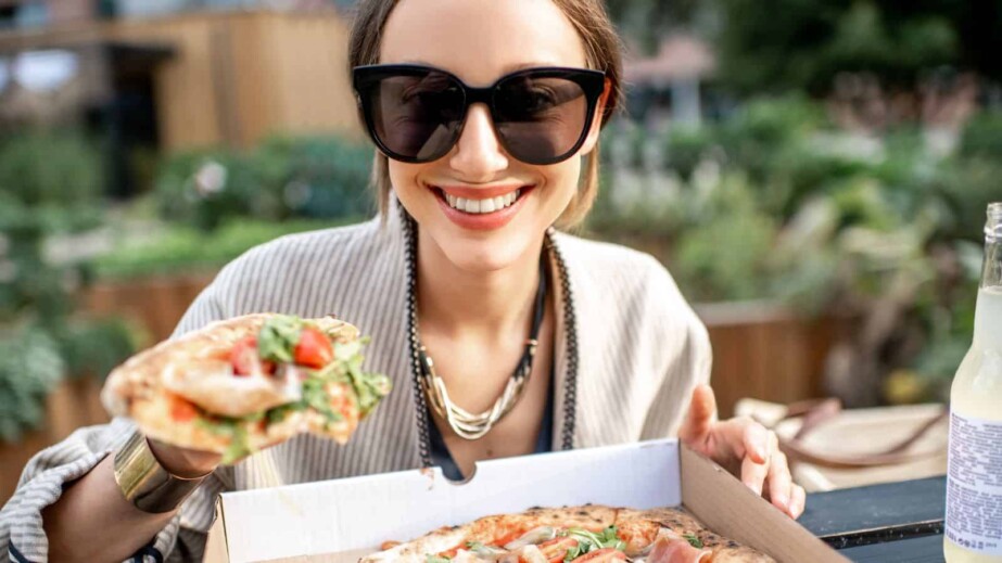 Woman eating pizza outdoors