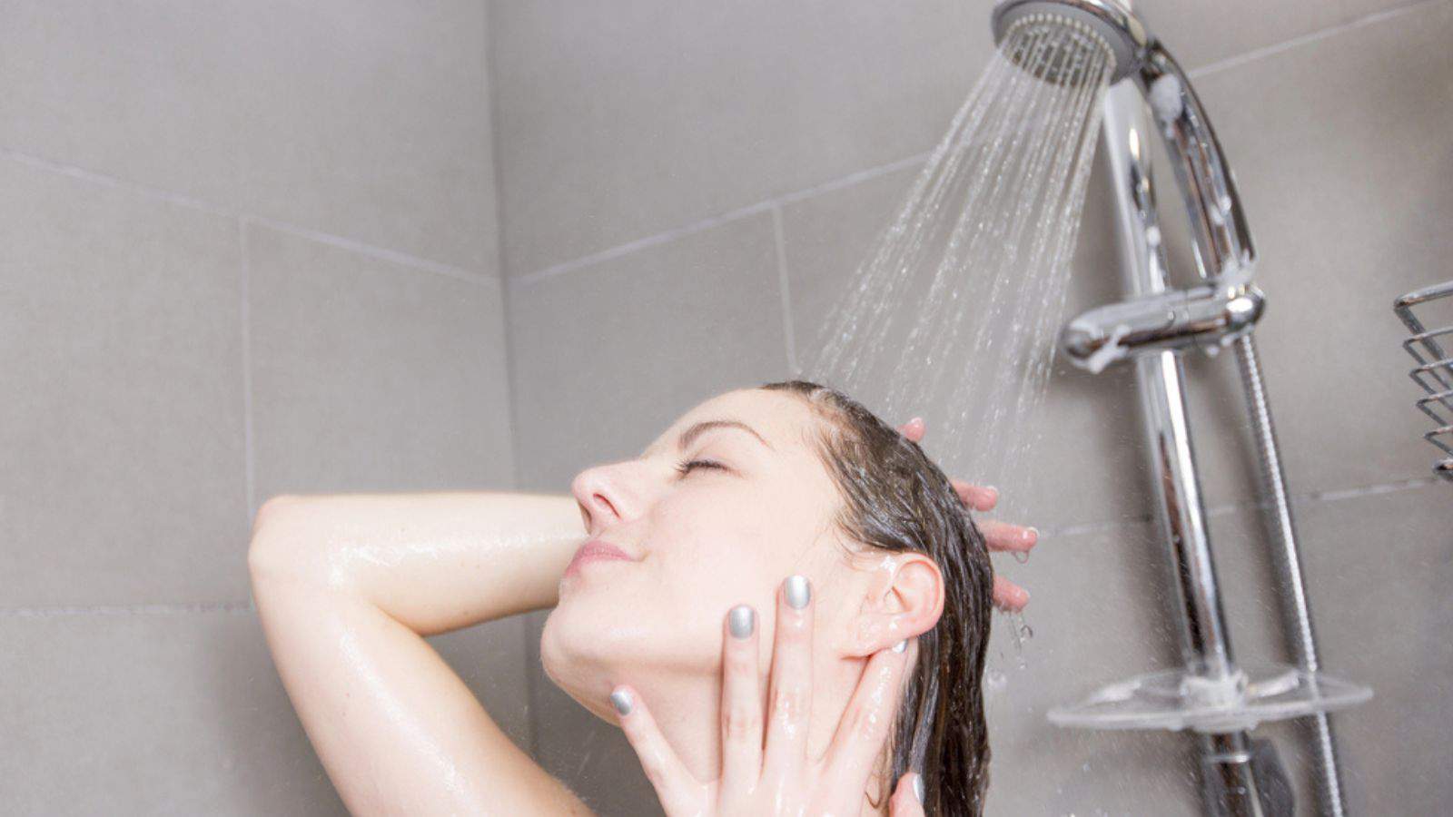Woman in shower washing hair with shampoo