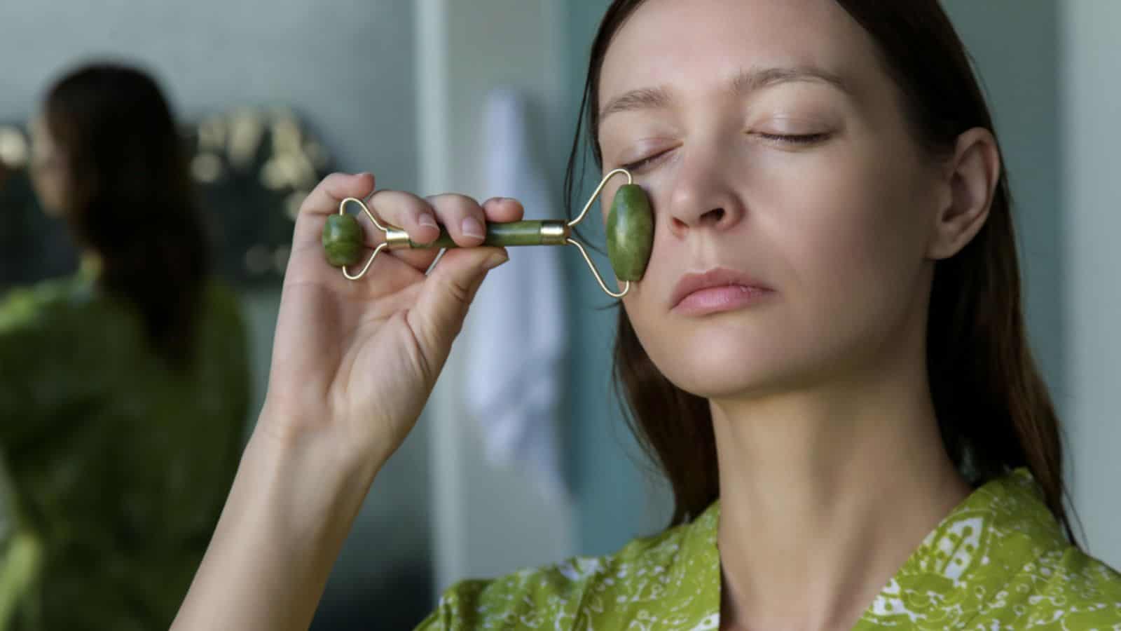 Woman using jade face roller for skin care