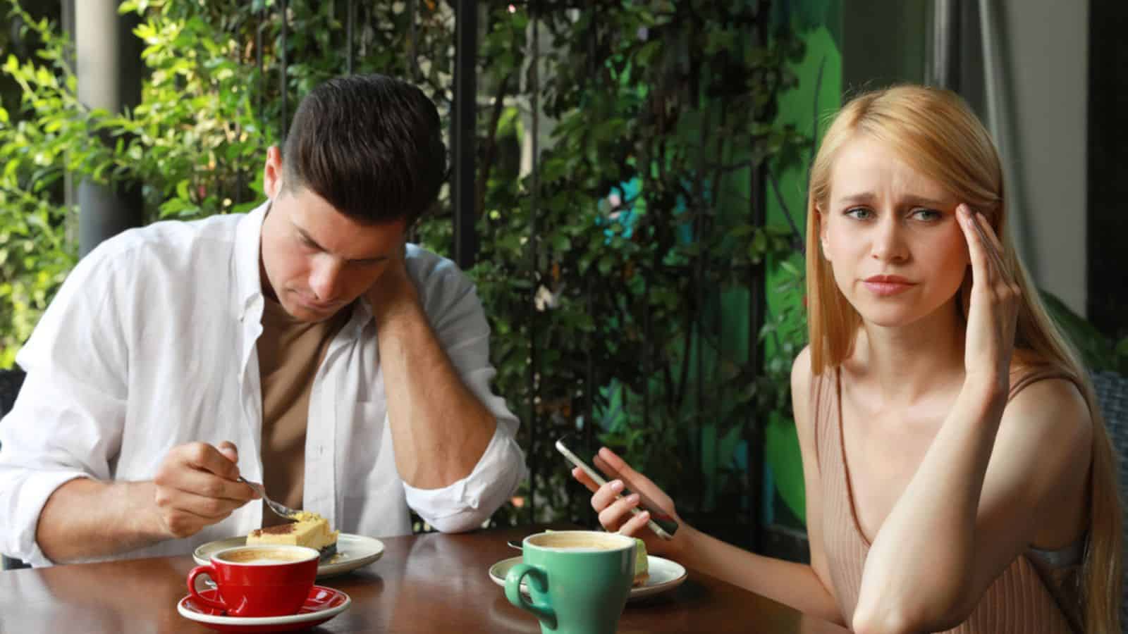 Woman with smartphone ignoring her boyfriend in outdoor cafe