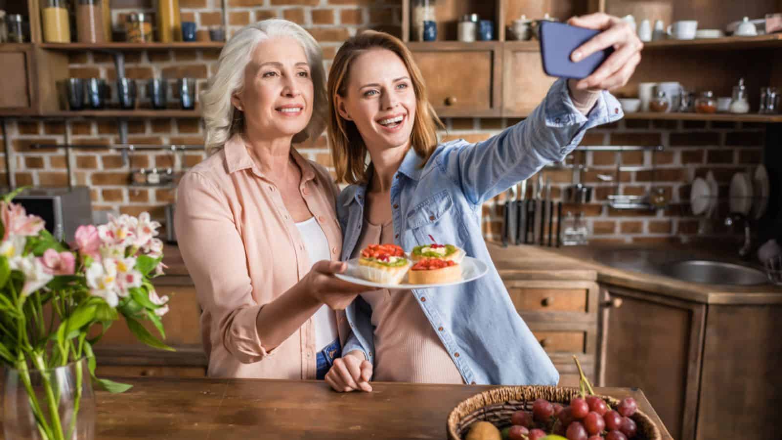 Woman and old mother taking selfie in kitchen