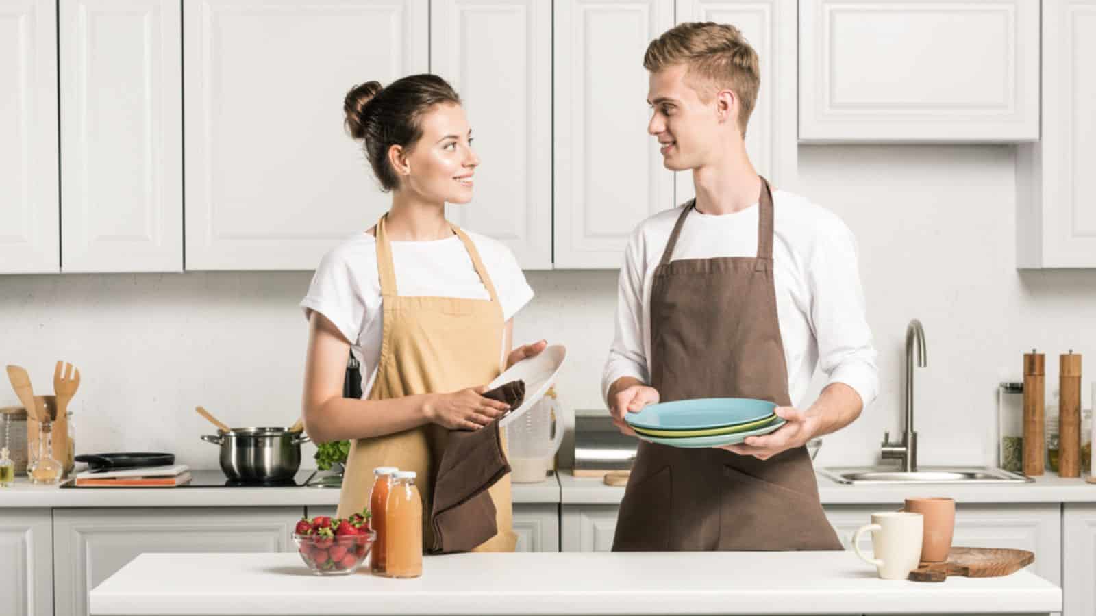 Young couple drying dishes in kitchen