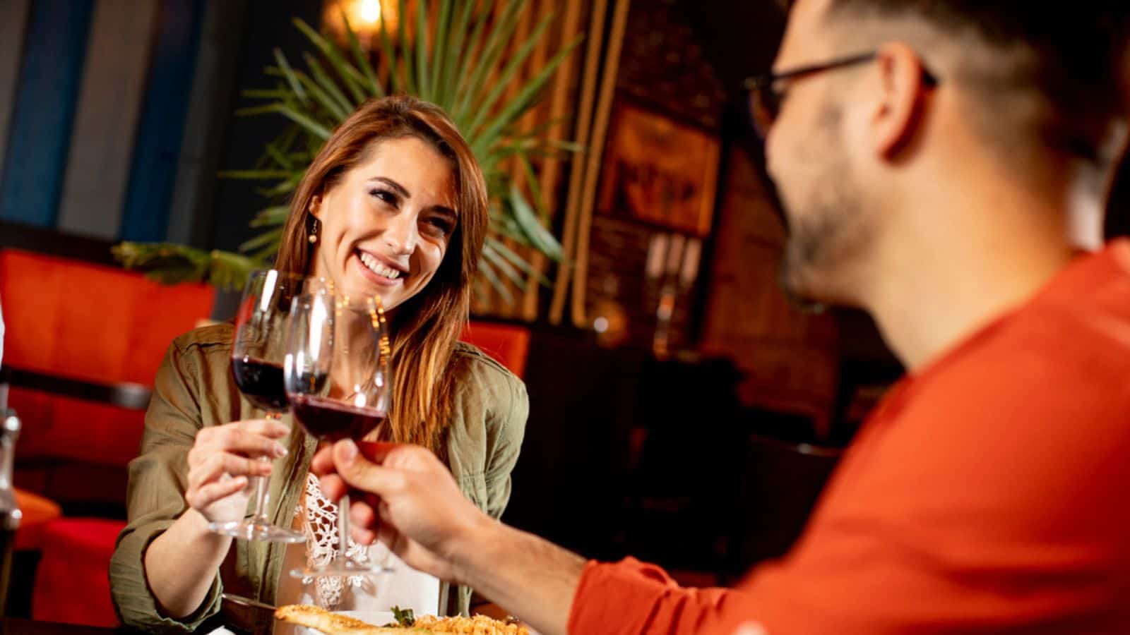 Young couple enjoying lunch in the restaurant with glasses of red wine