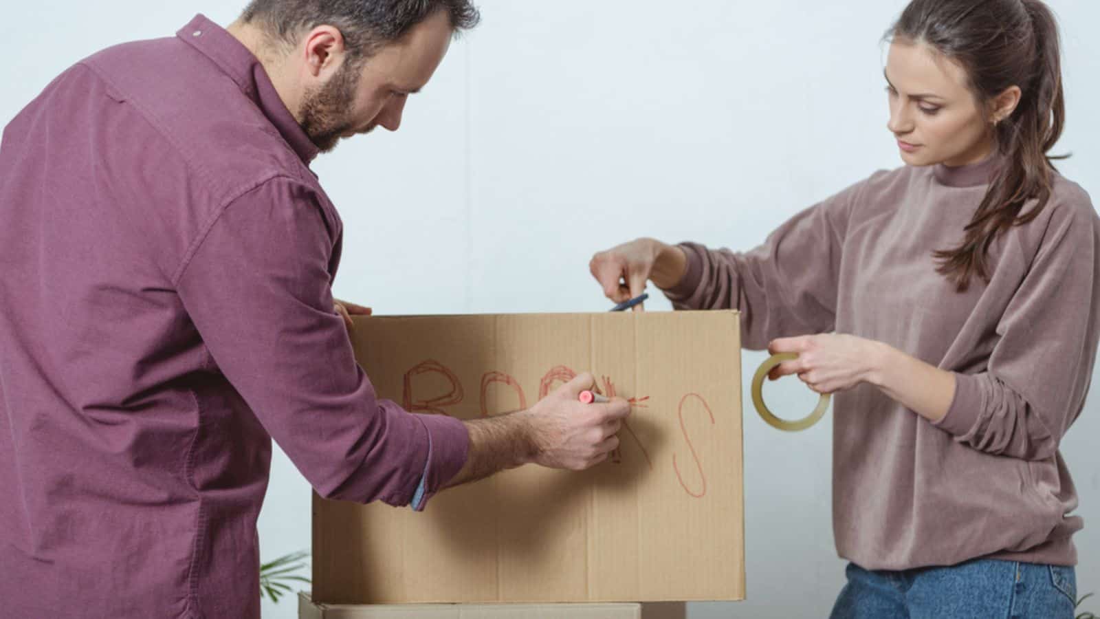 Young couple packing boxes while moving in new house