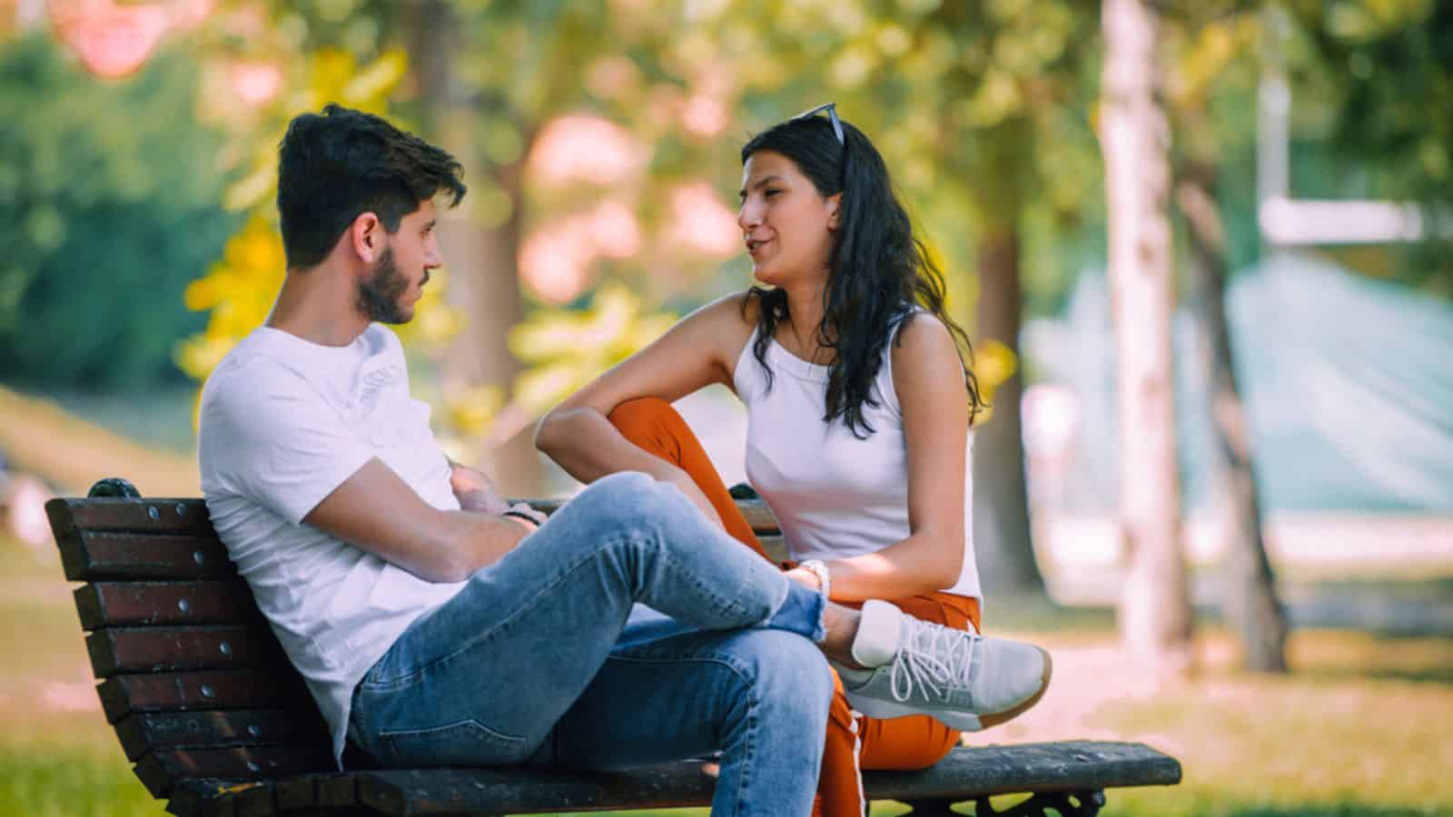 Young couple sitting on bench quarreling with each other at the park