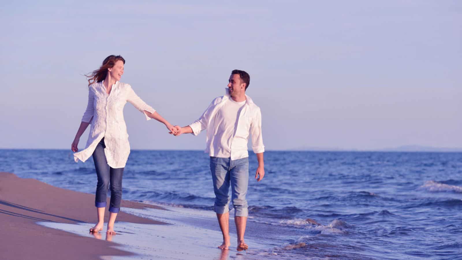 Young couple walking on beach have fun