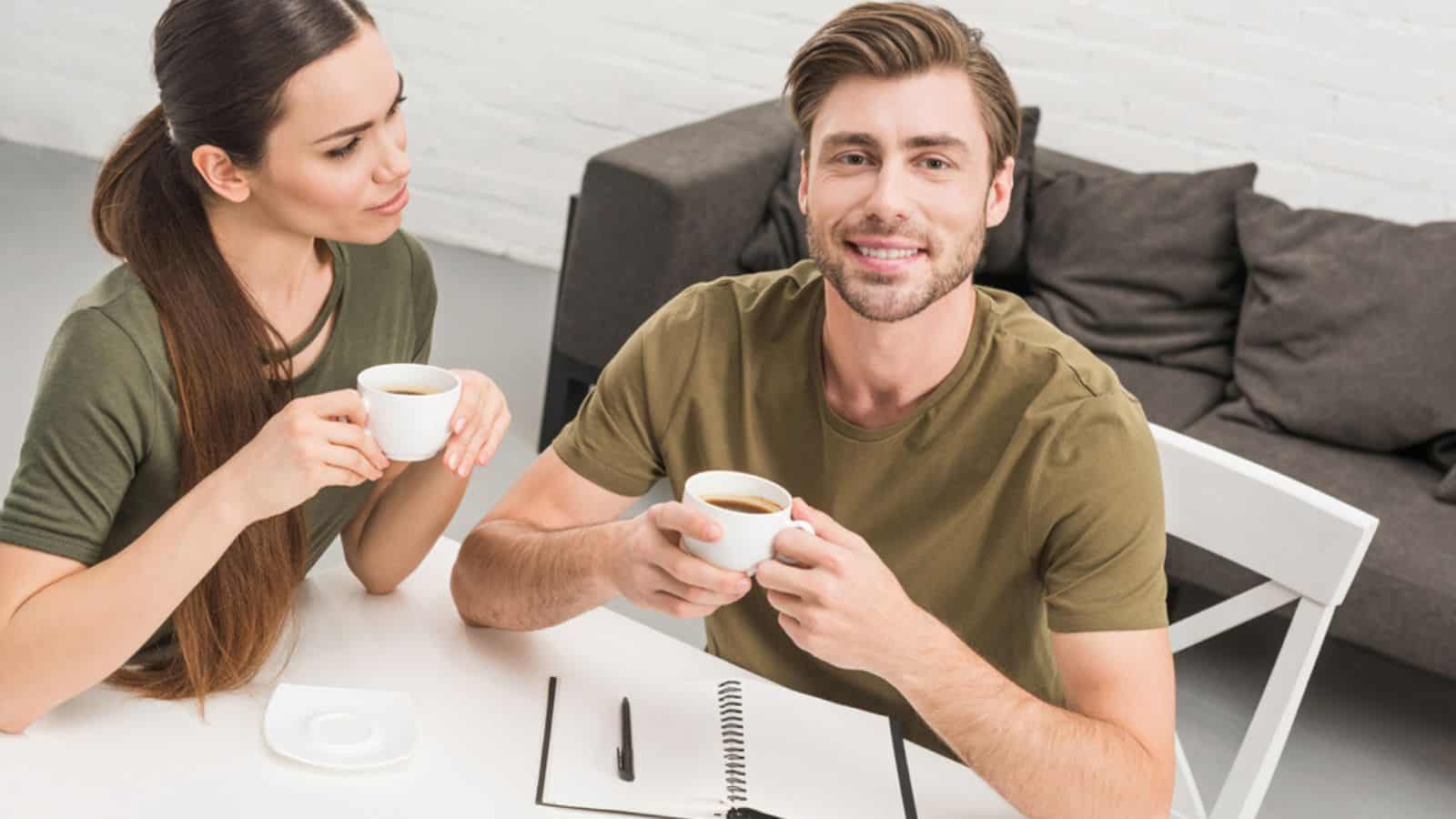 Young happy couple drinking coffee together at home