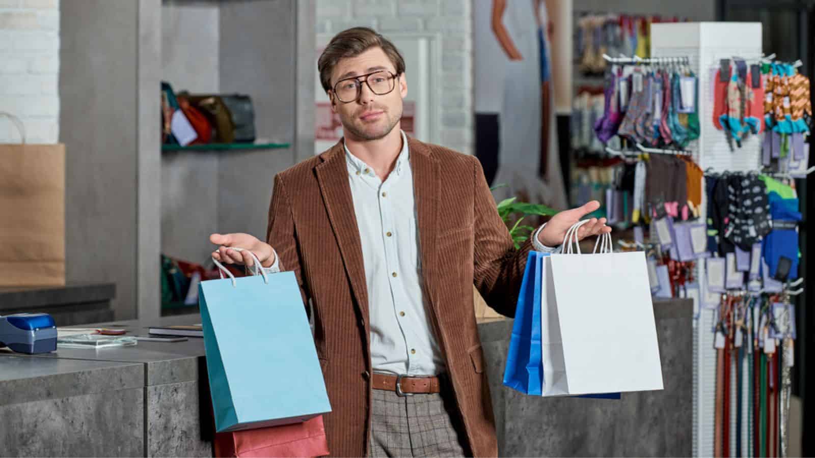 Young man in eyeglasses holding shopping bags