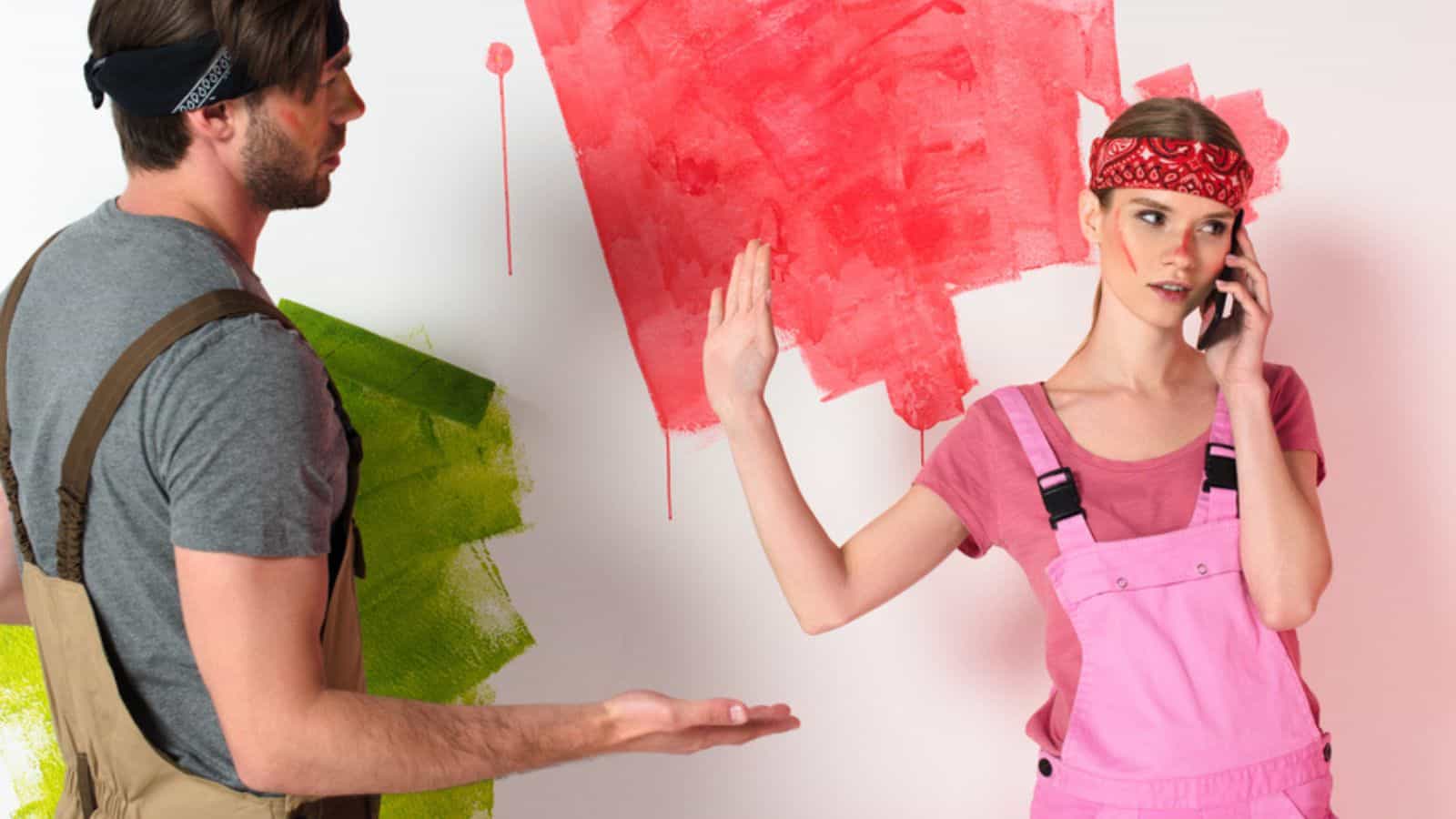 Young man in working overall pointing by hand to girlfriend