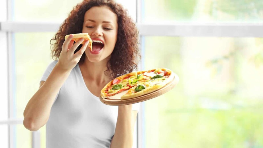Young woman eating tasty pizza